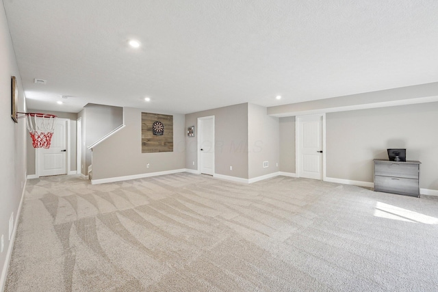 basement featuring light colored carpet and a textured ceiling