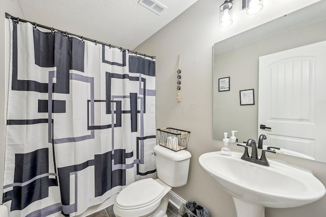 bathroom with sink, toilet, curtained shower, and a textured ceiling