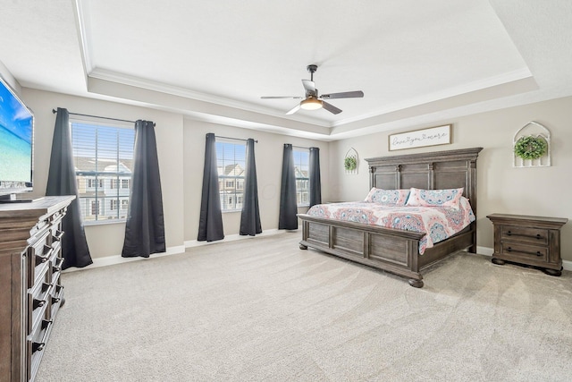 carpeted bedroom with ceiling fan, crown molding, and a raised ceiling