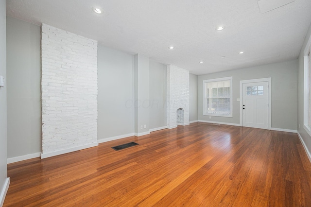 unfurnished living room with a textured ceiling, a fireplace, and hardwood / wood-style flooring