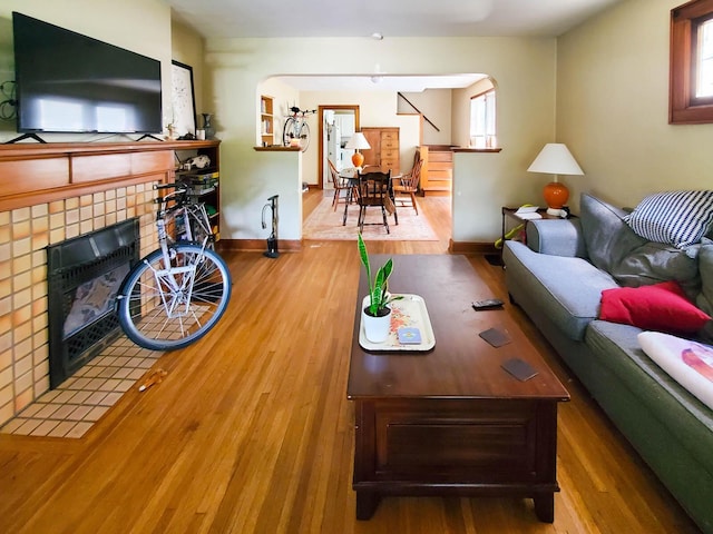 living room with a tiled fireplace and hardwood / wood-style flooring