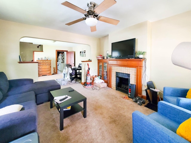 carpeted living room featuring ceiling fan and a tile fireplace