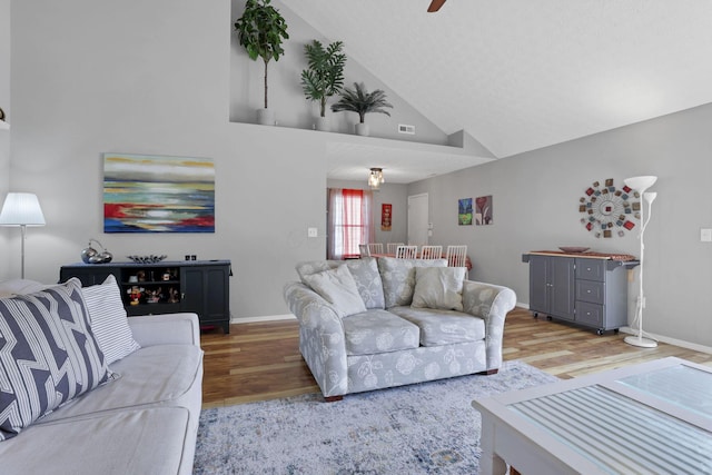 living room featuring hardwood / wood-style flooring, ceiling fan, and vaulted ceiling