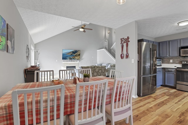 dining area with light hardwood / wood-style floors, a textured ceiling, lofted ceiling, and ceiling fan