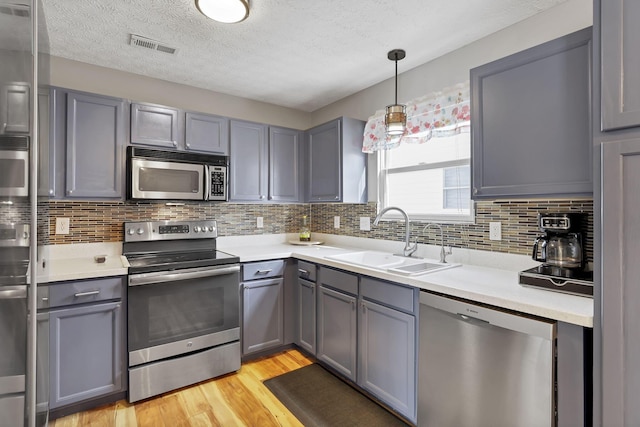 kitchen featuring sink, gray cabinets, stainless steel appliances, and light wood-type flooring