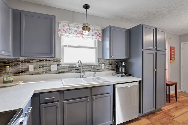 kitchen with appliances with stainless steel finishes, sink, hanging light fixtures, gray cabinets, and light wood-type flooring