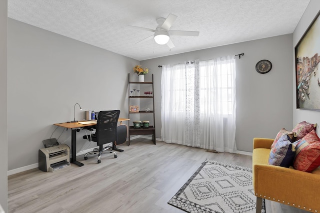 home office featuring ceiling fan, light hardwood / wood-style flooring, and a textured ceiling