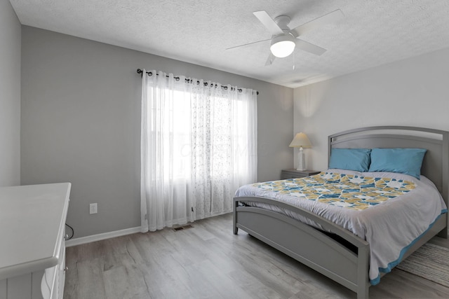 bedroom with light wood-type flooring, a textured ceiling, and ceiling fan