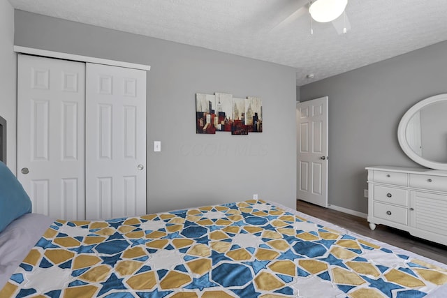 unfurnished bedroom with dark wood-type flooring, a textured ceiling, a closet, and ceiling fan