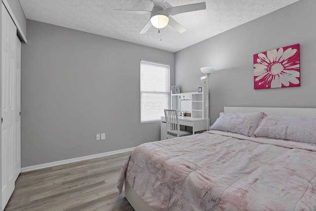 bedroom featuring light wood-type flooring, ceiling fan, a textured ceiling, and a closet