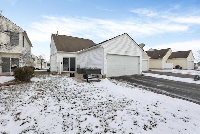 snow covered rear of property with a garage