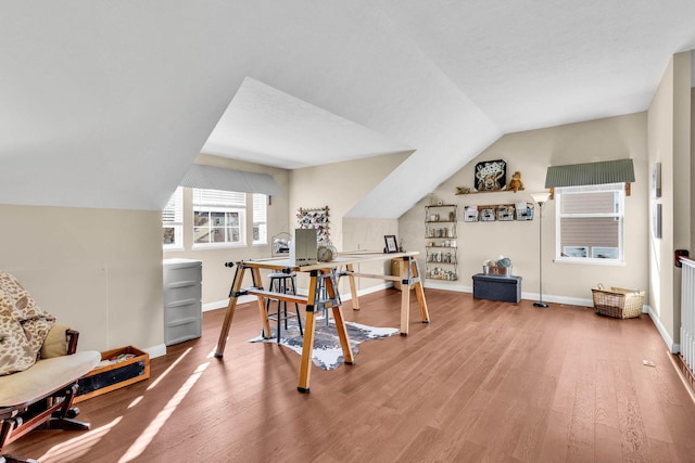 exercise area featuring lofted ceiling, wood finished floors, and baseboards