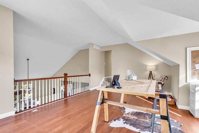 office area with vaulted ceiling, wood finished floors, visible vents, and baseboards