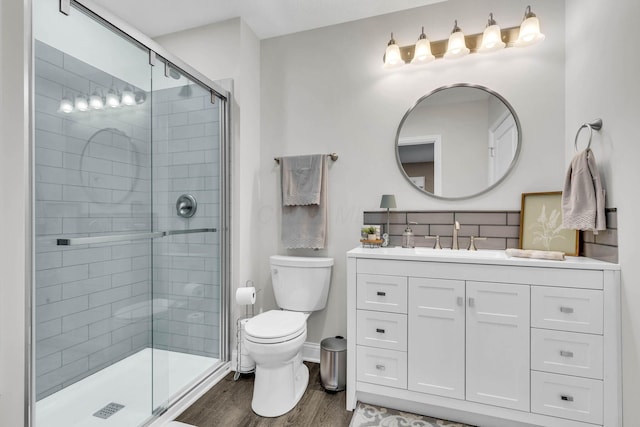 bathroom featuring vanity, wood finished floors, toilet, and a shower stall