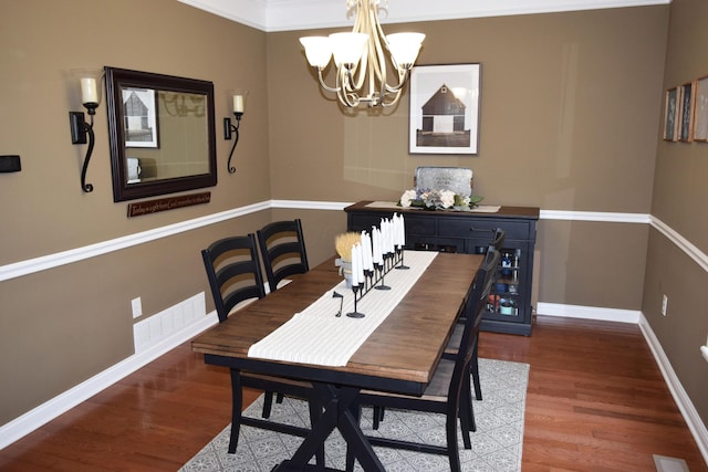 dining area featuring a notable chandelier, wood finished floors, visible vents, and baseboards