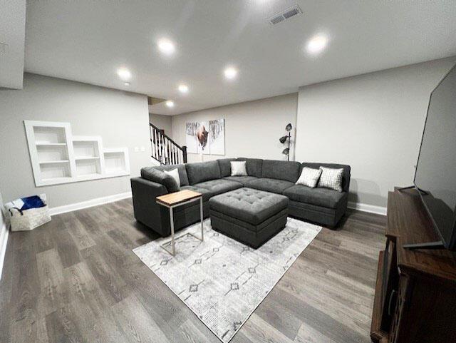 living room with recessed lighting, dark wood-style flooring, visible vents, baseboards, and stairway