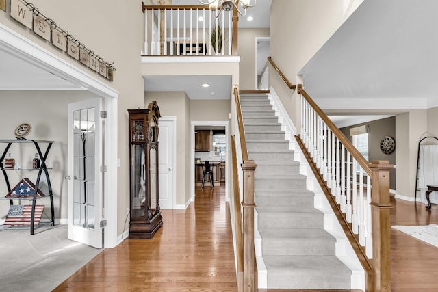 foyer with recessed lighting, a high ceiling, wood finished floors, baseboards, and stairs