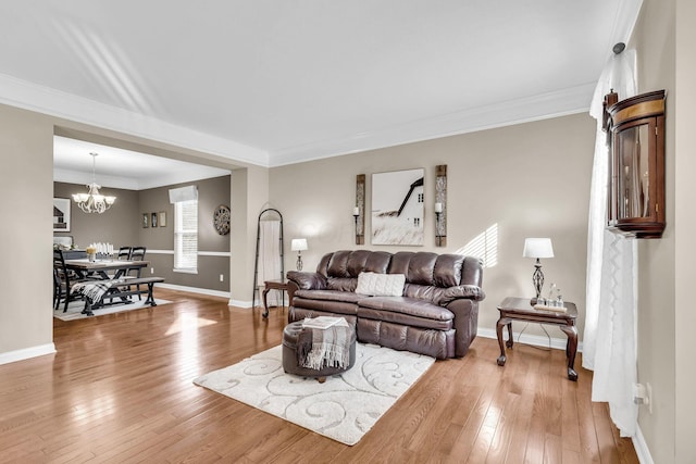 living area with a chandelier, crown molding, baseboards, and hardwood / wood-style flooring