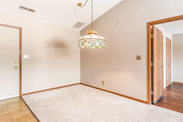 carpeted empty room with vaulted ceiling