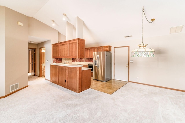 kitchen with pendant lighting, tasteful backsplash, stainless steel fridge with ice dispenser, kitchen peninsula, and light colored carpet