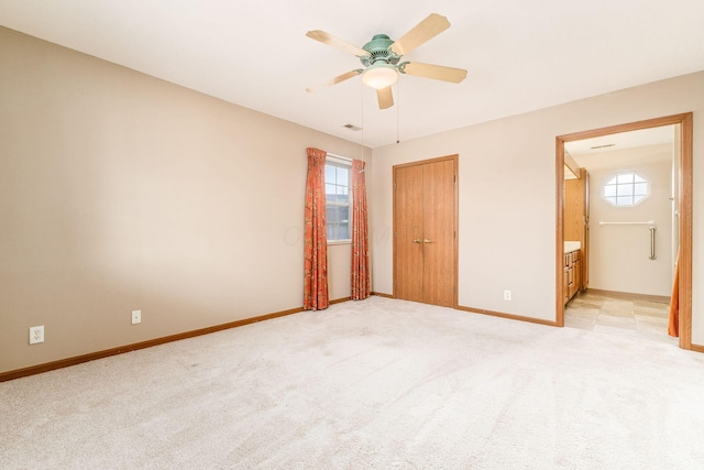 unfurnished bedroom featuring ceiling fan, light carpet, and ensuite bath