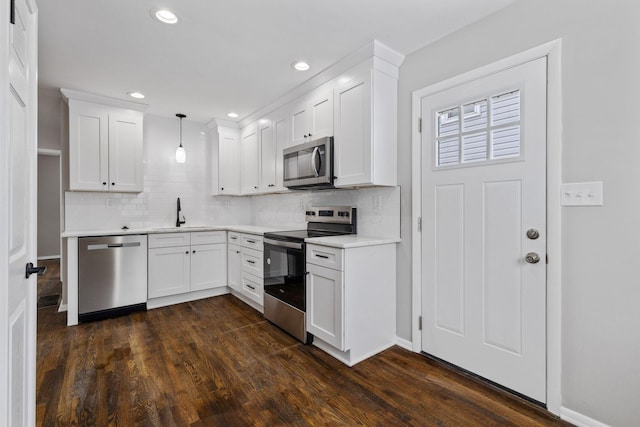 kitchen with appliances with stainless steel finishes, dark hardwood / wood-style floors, decorative light fixtures, sink, and white cabinets