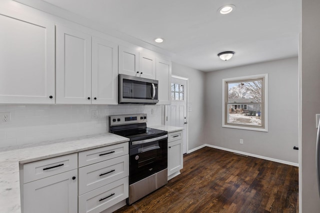 kitchen featuring appliances with stainless steel finishes, white cabinets, backsplash, light stone counters, and dark wood-type flooring