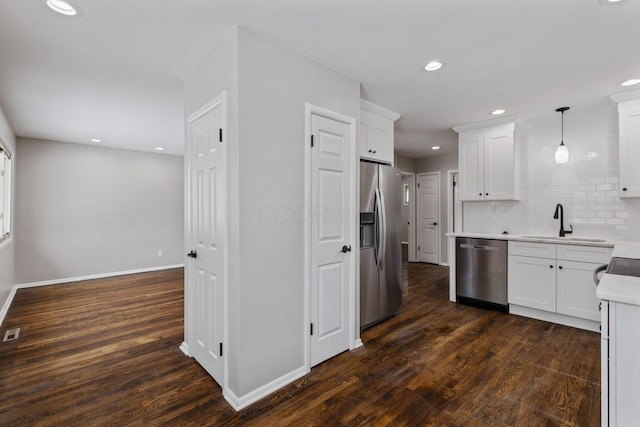 kitchen with sink, dark wood-type flooring, hanging light fixtures, stainless steel appliances, and white cabinets