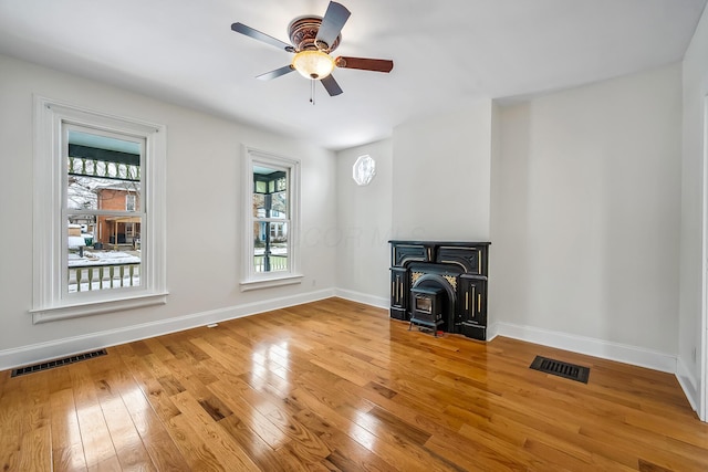 unfurnished living room featuring light hardwood / wood-style flooring, a wealth of natural light, and a wood stove