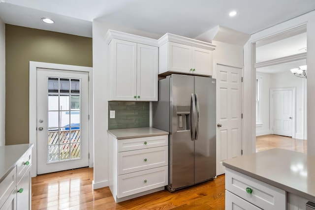 kitchen featuring decorative backsplash, light hardwood / wood-style floors, white cabinetry, and stainless steel fridge with ice dispenser