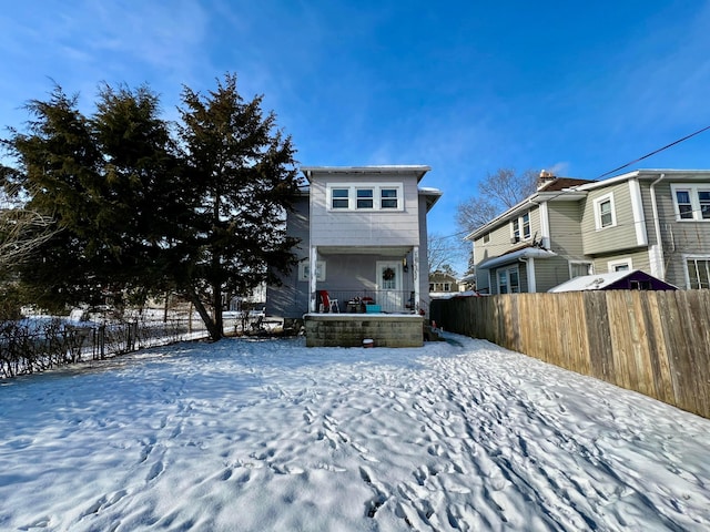 snow covered rear of property with a porch