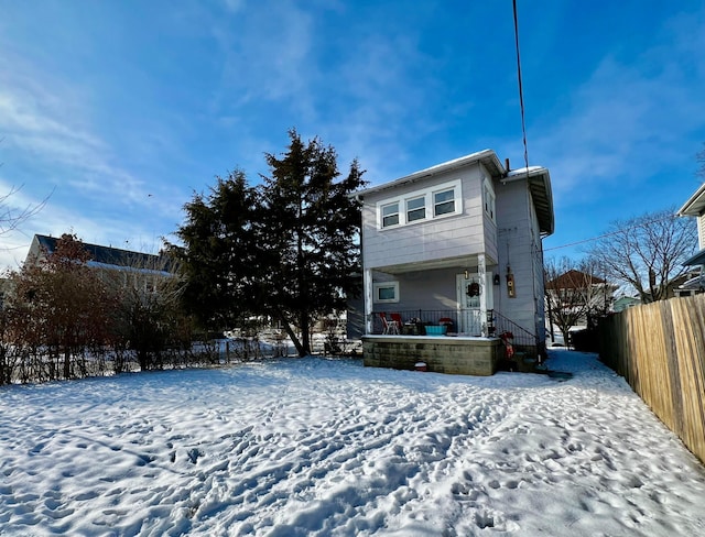 snow covered rear of property with covered porch