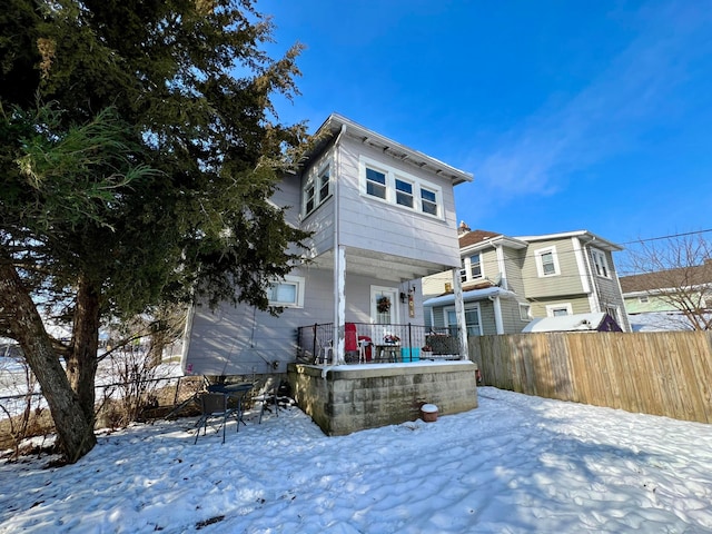 snow covered rear of property with covered porch