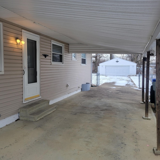 snow covered patio featuring a garage and an outdoor structure