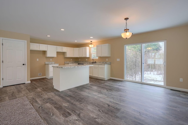 kitchen featuring pendant lighting, dark hardwood / wood-style flooring, sink, white cabinets, and a center island