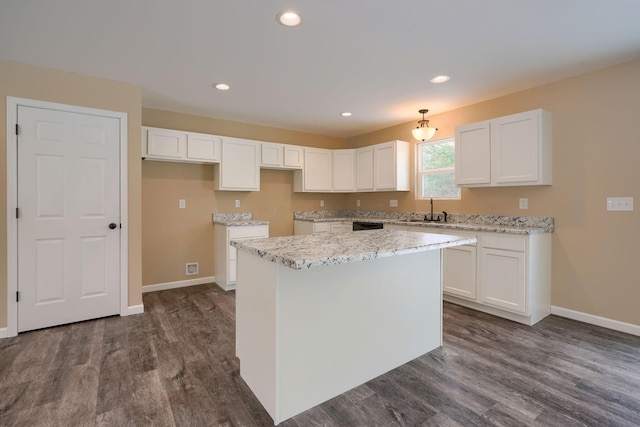 kitchen featuring a center island, light stone countertops, white cabinets, sink, and dark hardwood / wood-style flooring