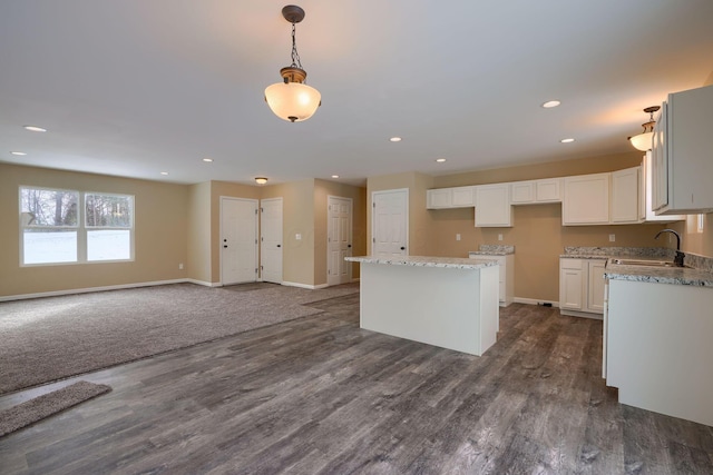 kitchen with a center island, decorative light fixtures, dark wood-type flooring, white cabinetry, and sink