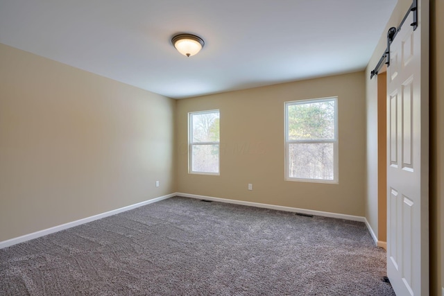 carpeted spare room with a barn door