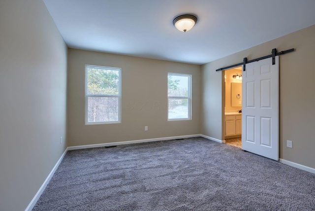 carpeted empty room featuring a barn door and a healthy amount of sunlight