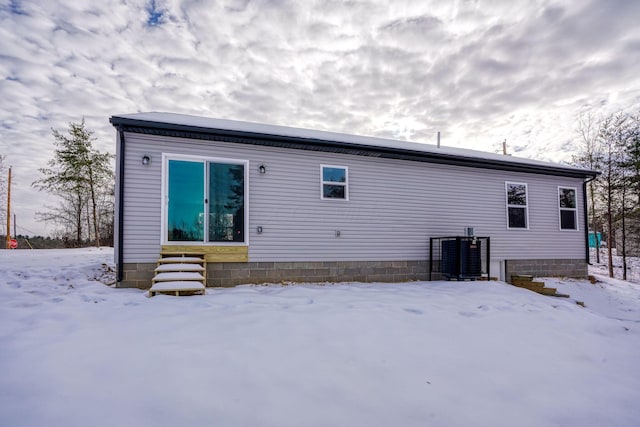 snow covered rear of property with central AC unit