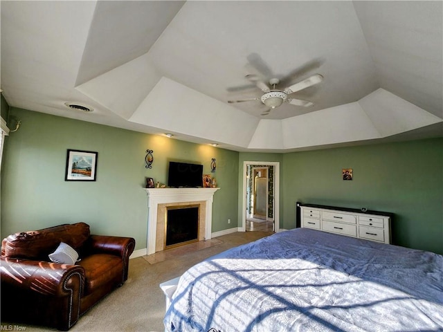 carpeted bedroom featuring a raised ceiling and ceiling fan