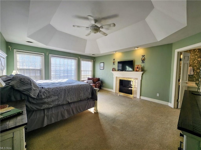 carpeted bedroom featuring multiple windows, a raised ceiling, and ceiling fan