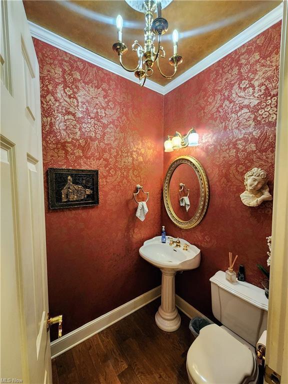 bathroom featuring an inviting chandelier, wood-type flooring, ornamental molding, and toilet