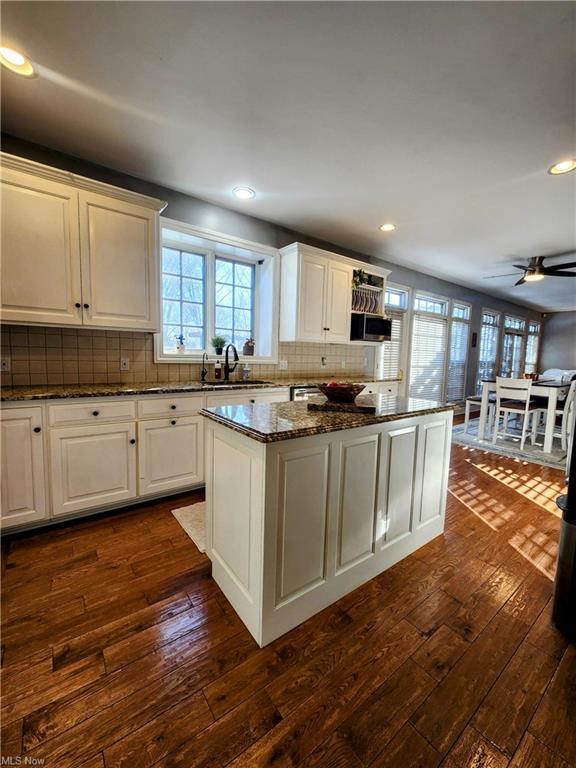 kitchen featuring white cabinetry, dark wood-type flooring, dark stone counters, and a center island