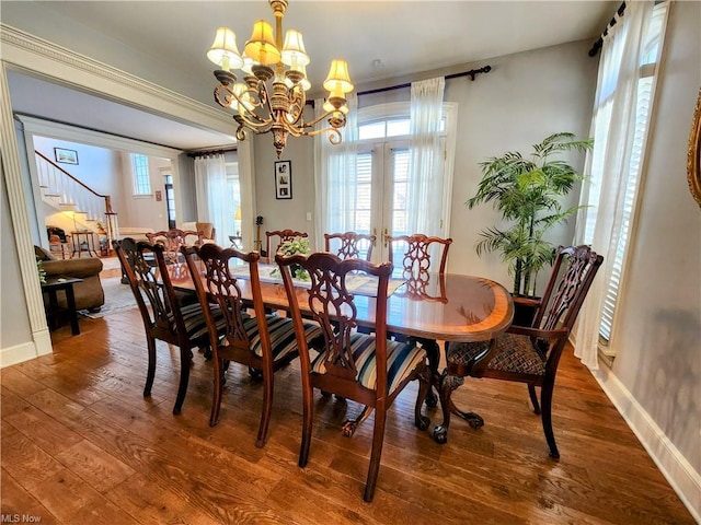 dining room with hardwood / wood-style floors, an inviting chandelier, and french doors