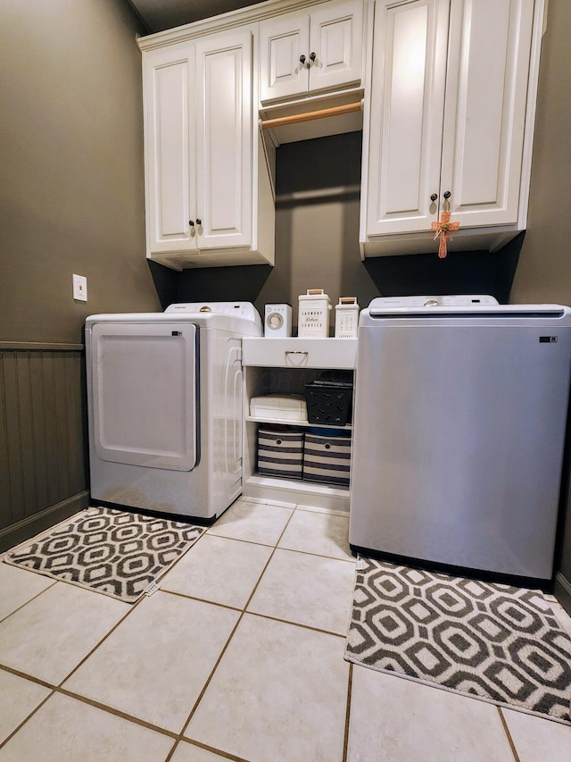 laundry room with cabinets, light tile patterned flooring, and washing machine and clothes dryer