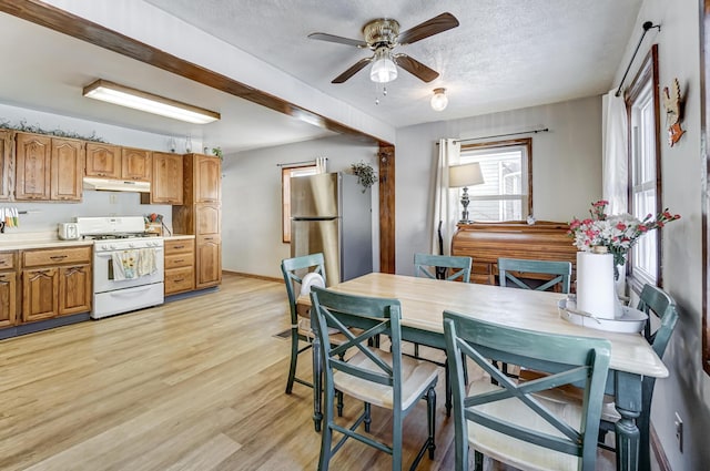 kitchen featuring light hardwood / wood-style floors, a textured ceiling, gas range gas stove, ceiling fan, and stainless steel fridge