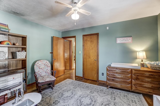 living area with ceiling fan, wood-type flooring, and a textured ceiling