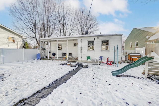 snow covered rear of property featuring a playground