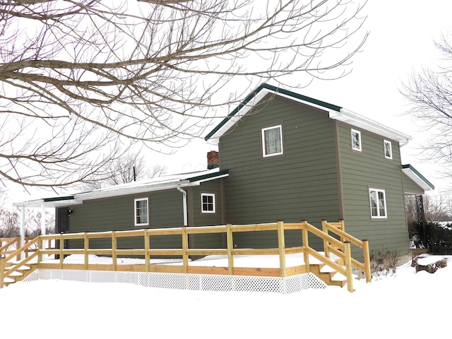 snow covered rear of property with a wooden deck